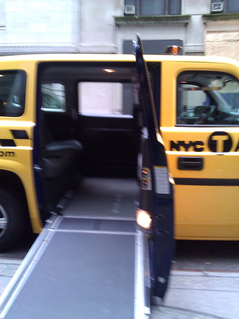larger photo of a ramp extended outside of a yellow Nissan MV-1