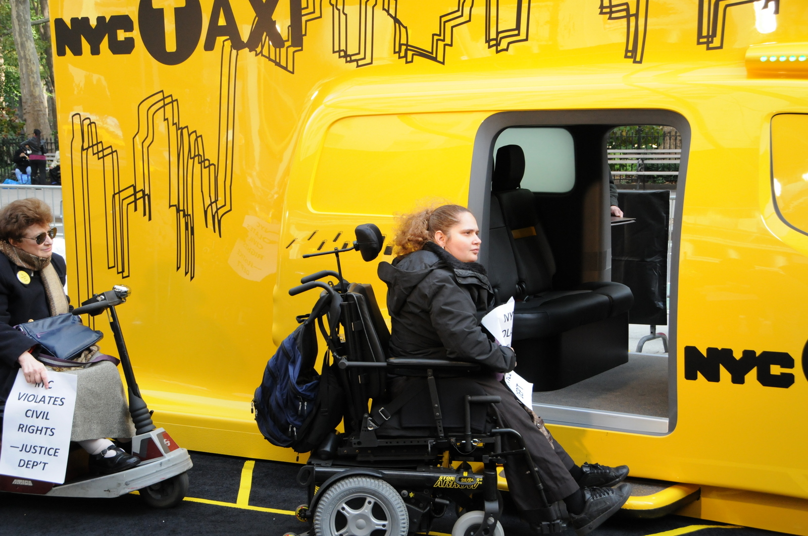 larger photo of a woman in a wheelchair at an inaccessible entrance to the taxicab