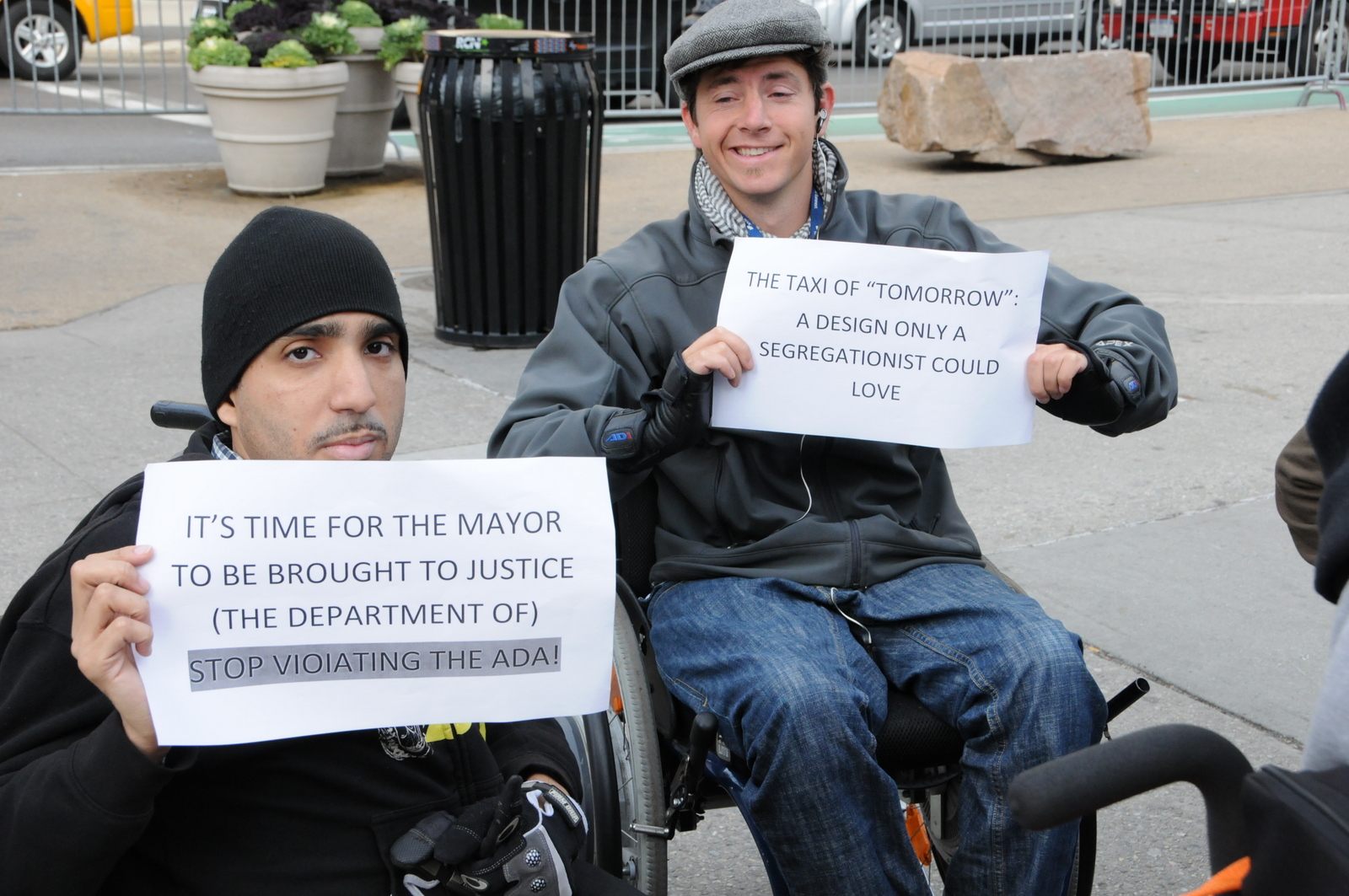 photo of two wheelchair users holding signs
