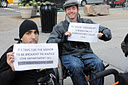 photo of two wheelchair users holding signs