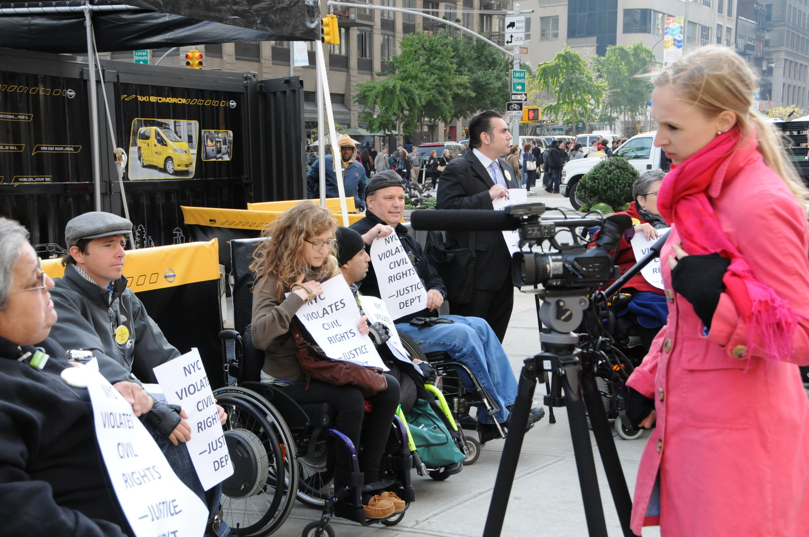 photo of a news camera filming, or ready to film, protestors in wheelchairs