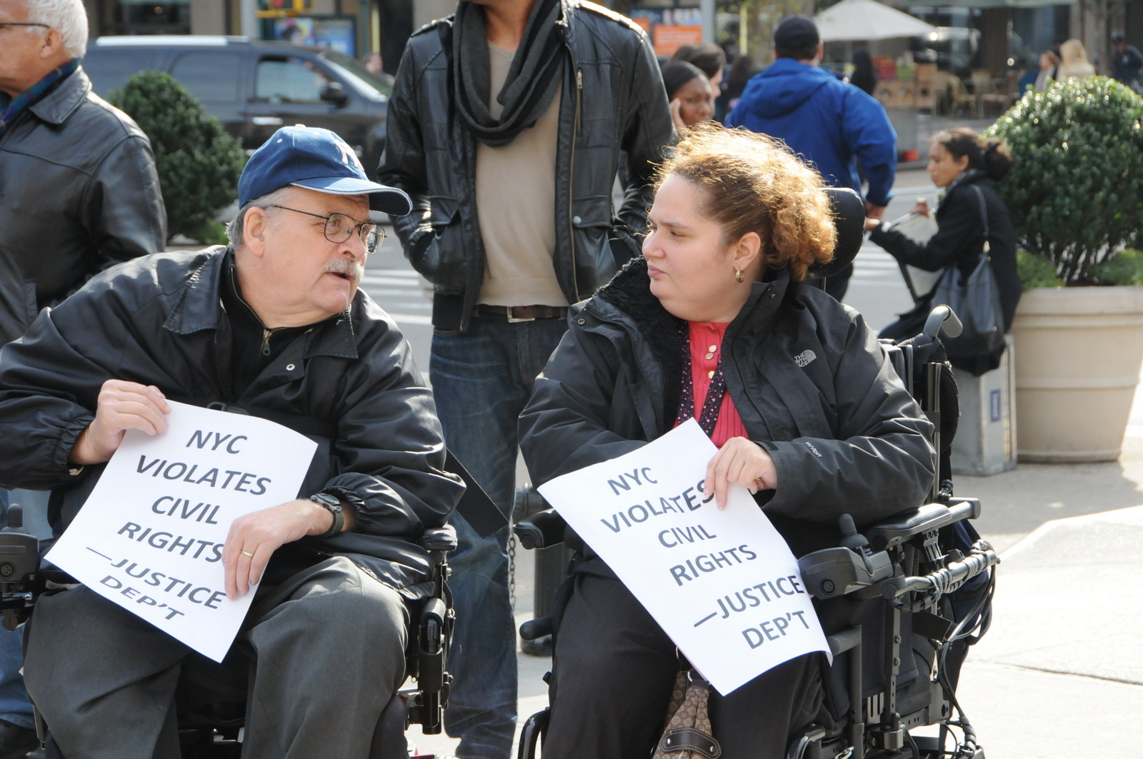 photo of two of the demonstrators, in wheelchairs, chatting with each other