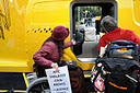 photo of two demonstrators in wheelchairs looking at Taxi's inaccessible entrance